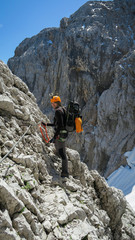 Tourist with equipment on the via ferrata trail in the alps