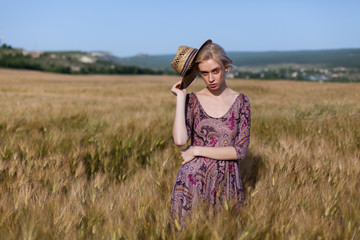 Portrait of a farmer woman in a dress in a field of rye harvest