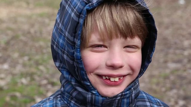 Closeup view video portrait of cute funny little boy smiling and laughing sincerely looking at camera standing outdoor in spring park.