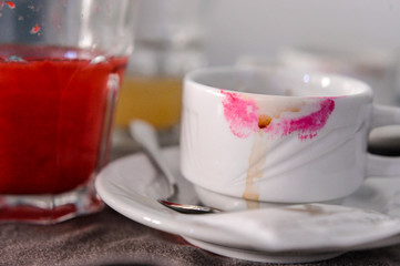 Tazzina di caffè sporca di rossetto vicino a bicchiere di succo