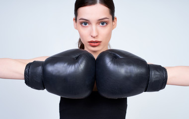 Serious athletic caucasian girl in black boxing gloves.