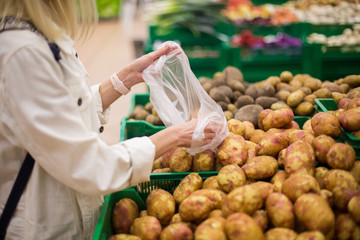 A woman holds potato. Buying Fresh Farm Bio Vegetarian Products in grocery market