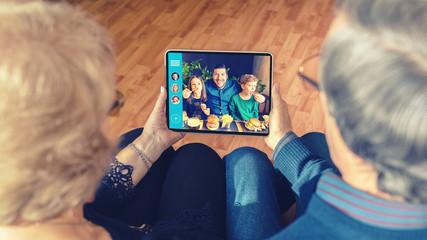 Senior couple chatting on video call with son and grandchildren due to home isolation quarantine