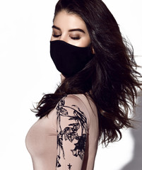 Young beautiful slim brunette woman in sexy longsleeve wearing black mask for protection from coronavirus infection