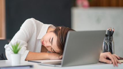 Portrait of beautiful young business woman sleeping at her workplace.