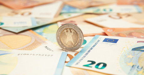 Euro coin rolls against a background of banknotes.