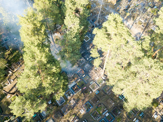 Fire in a forest cemetery. Smoke envelops conifers. Aerial drone view.