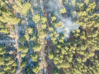 Fire in a forest cemetery. Smoke envelops conifers. Aerial drone view.