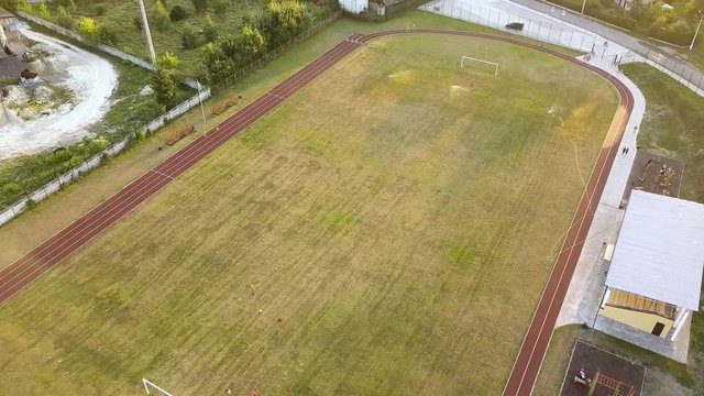 Top down aerial view of football field surface covered with green grass and sprinklers spraying water.