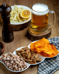 beer snacks, a mug of beer, and a dish with lemon and string cheese