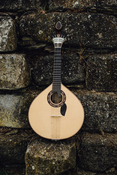 Traditional portuguese guitar, front view, stone wall background