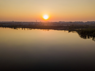 Sunset over the lake in the city. Aerial drone view.