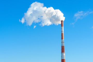large blue pipe releases white steam into the blue sky. space for text, copy space