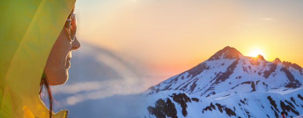 Banner, a girl looks at a beautiful sunset on top of the mountains