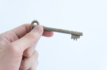 Woman or man hand holding key before opening door. Isolated on white background. Close up