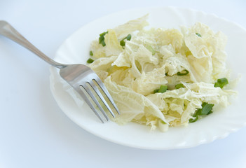 Tasty green salad on a white plate and a fork. Isolated on white background. Close up