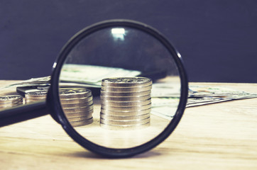 A stack of coins is visible through a magnifying glass. Business concept. Close-up.