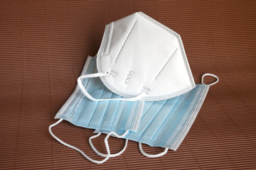 Obraz na płótnie Canvas white KN95 or N95 mask with antiviral medical mask for protection against coronavirus on brown background. Surgical protective mask. prevention of the spread of virus and pandemic COVID-19.