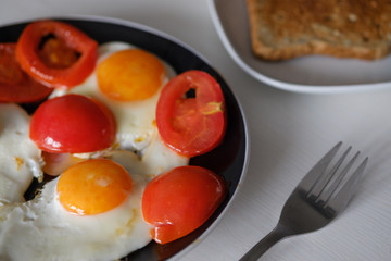 Fried eggs with tomatoes and bread for breakfast on a white background.