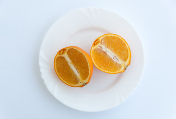 Two halves of an orange on a plate isolated on a white background. Top view