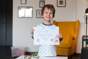 Cute little boy showing card against home interior