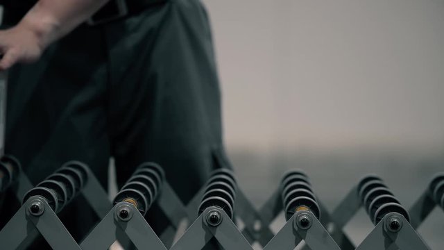 An operator pushes a package on the packaging line in a warehouse. The parcel moves with the help of the operator on the conveyor. Automation of online shipping logistics