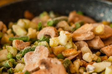 Close-up of frozen mushrooms mixed with peas, asparagus and zucchini. Mixture for healthy and balanced nutrition.