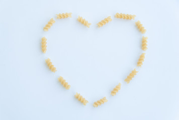 Top view of italian pasta in a heart shape, fusilli isolated on white background