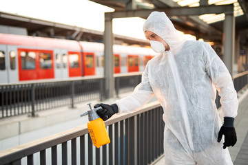 Ein Mann in einem Schutzanzug desinfiziert Flächen im öffentlichen Raum um die Ausbreitung des Coronavirus einzudämmen