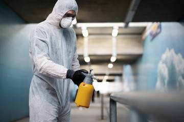 Ein Mann in einem Schutzanzug desinfiziert Flächen im öffentlichen Raum um die Ausbreitung des Coronavirus einzudämmen - 337709912