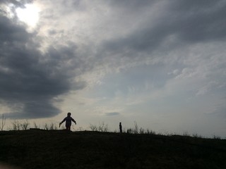 Obraz na płótnie Canvas silhouette of a child running on a desert hill against the evening sky