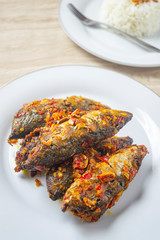 ikan balado in white plate. indonesian food made from fried fish cooked with red chili. has a savory and spicy taste and has good nutritional content for the body