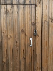brown wooden door in the fence with a white handle and padlock