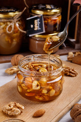 Jar of honey on a wooden board. Honey with nuts.