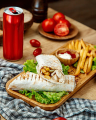 chicken pita roll and french fries on a wooden board