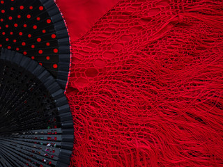 Black open fans for flamenco dancing on a red Spanish shawl. Background for a flamenco school or dance website or postcard. Mockup for the designer. Bright background in Spanish style with copy space - obrazy, fototapety, plakaty