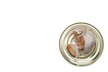 A head of garlic lies on a tin can. The picture is isolated on a white background. View from above