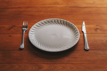 Porcelain plate and cutlery against a wood background