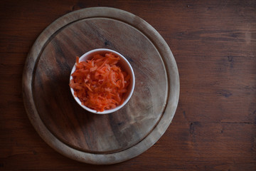 Top view of pair carrots cut into slices on rustic wooden plate. Concept: vegetables, work in the kitchen, natural food