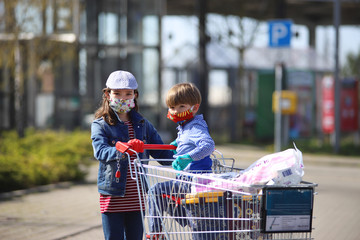 Ein Mädchen geht mit ihrem Bruder mit Mundschutz einkaufen