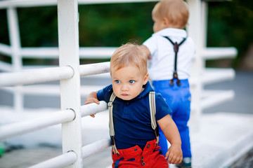 Fototapeta na wymiar portrait of a boy with blond hair and blue eyes European appearance. A boy in a polo and suspenders on the street