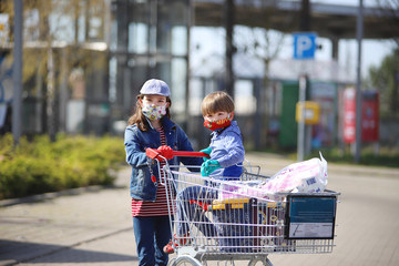 Ein Mädchen geht mit ihrem Bruder mit Mundschutz einkaufen