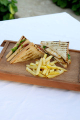 club sandwich with french fries on wooden board