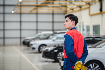 Asian motorcyclists wear racing suits in repair shops and auto repair centers. The background is a stock of cars