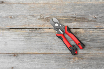 Scissors for cutting and Stripping wires on a gray wooden table. An electrician's or Builder's tool. Top view with space for text