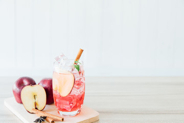 Red apple soda ice in a glass with the herb of cinnamon on wooden background