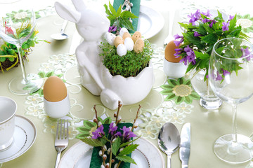 Elegant Easter holiday table settings decoration with fresh early spring violet flowers, cress leaves and eggs.