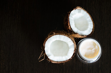 top view on natural cosmetic product. coconut and solid butter, oil,cream, organic massage cosmetics on dark brown wooden background with copy space