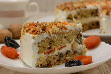 Fruit cake, a piece on a plate with dried fruits. Wood background