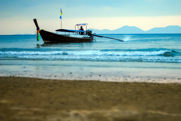 Fototapeta premium Silhouette of fisherman in the sea, driving a motor boat near the shore at dawn
